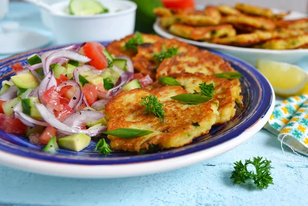 Potato pancakes with vegetable salad on a blue background