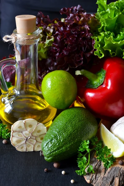 Fresh ripe vegetables, olive oil, lettuce on a black background