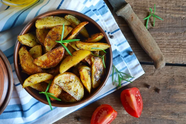 Baked potato wedges with rosemary and garlic on a wooden backgro