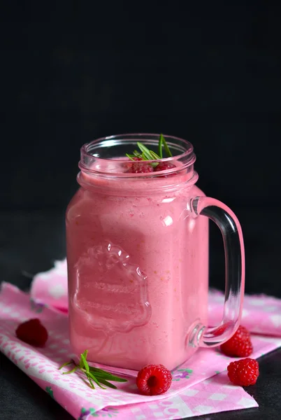 Summer cool drink, a smoothie with raspberry and peach on a blac