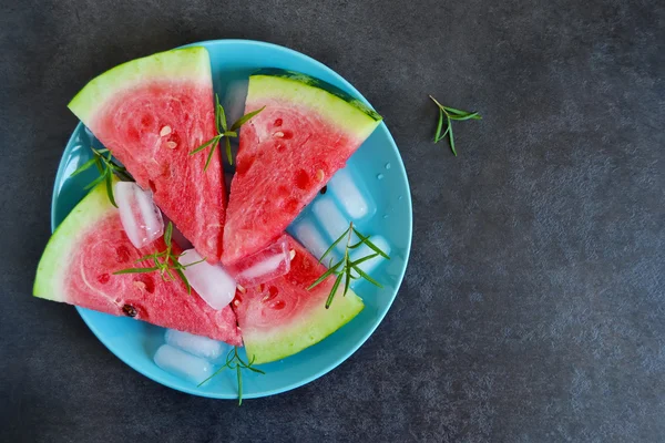 Background of fresh watermelon slices with ice on a black backgr