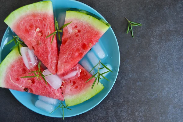 Background of fresh watermelon slices with ice on a black backgr