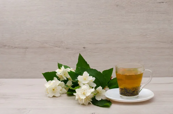 Women's arms around a mug of jasmine tea, top view on a background of wooden planks