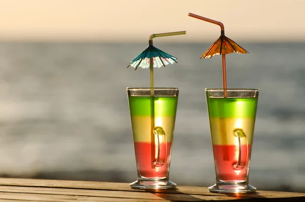 Two colorful cocktails in the morning sun on the sea background, close-up, empty space