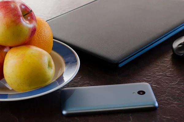 Apples and smart phone on the table next to the laptop. Healthy break