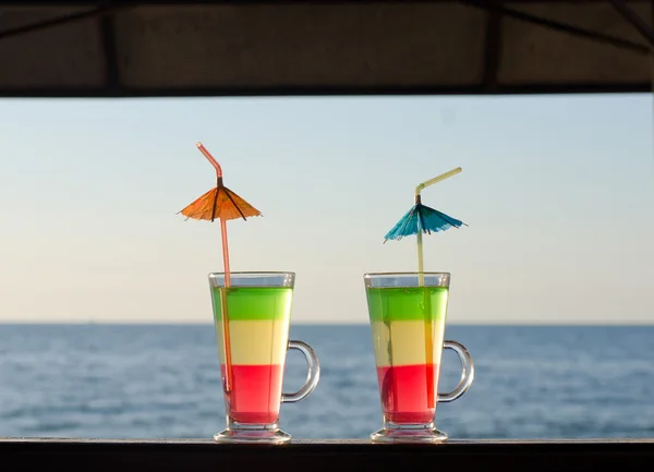 Two tricolor cocktail on the bar counter on a sea-view