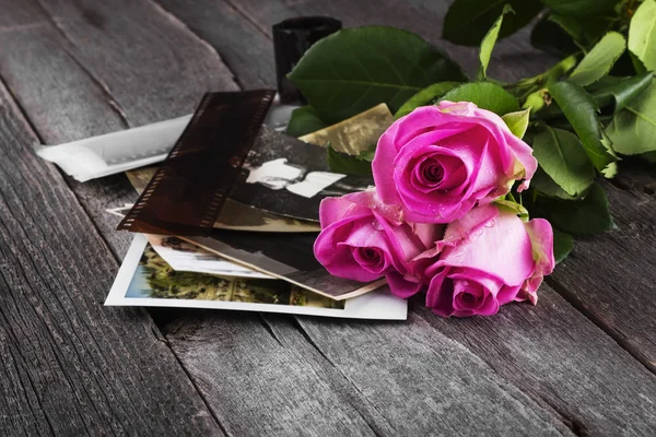 Old photos pink roses and chocolate on a dark wooden background