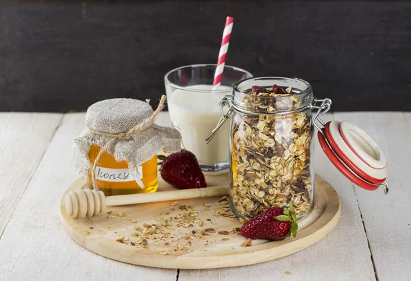 Granola with nuts in glass jar, strawberry, glass of milk and ja