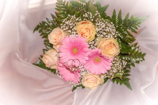 Bridal bouquet with rings on peach roses and pink gerberas