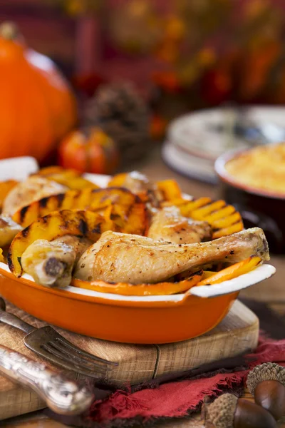 Oven roasted chicken with grilled pumpkin on a rustic table