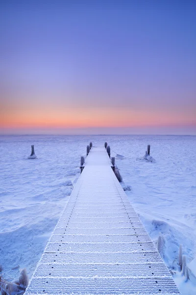 Jetty on a frozen lake in The Netherlands at sunrise