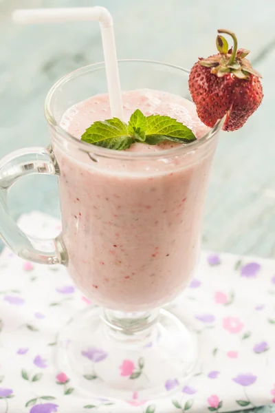 A glass of strawberry milk shake with fresh strawberries and min