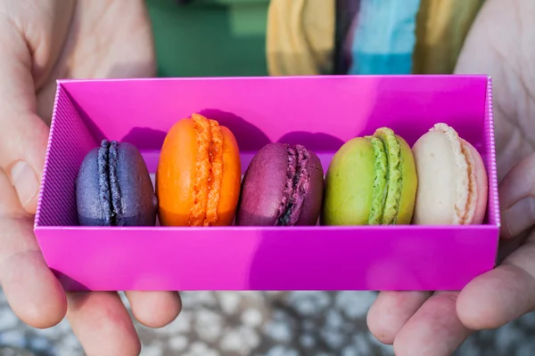 Multicolored macaroon cake in a pink box in the han