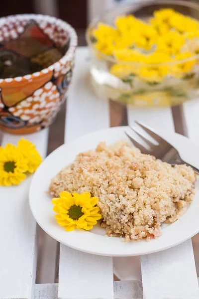 Piece of cake with crumbs, tea and yellow flowers on white woode