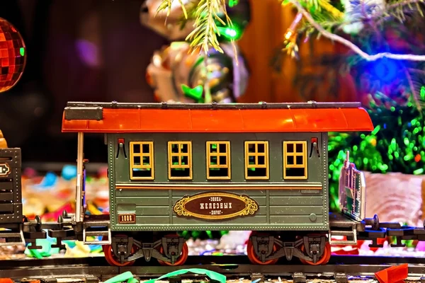 Christmas toy railroad near a Christmas tree with lights