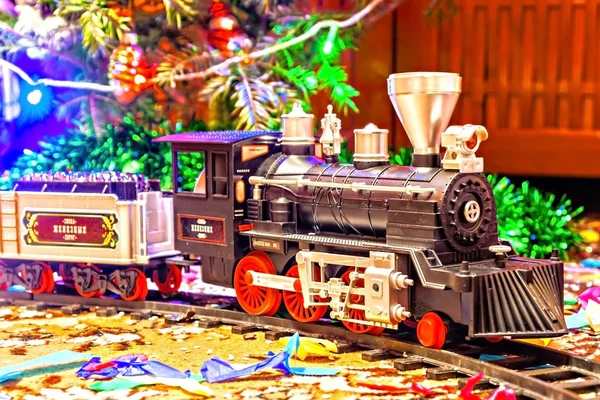 Christmas toy railroad near a Christmas tree with lights