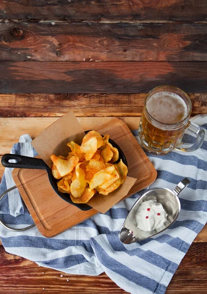 Crackling tasty snack from potato chips and spicy dip and glass