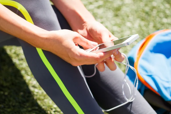 Slose Up Sporty woman holding phone with empty screen sitting on