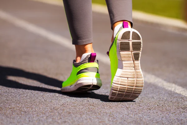 Runner feet running on road closeup on shoe. Woman fitness jog w