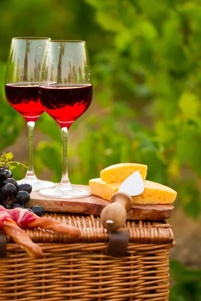 Two glasses of red wine with bread, meat, grape and cheese on th