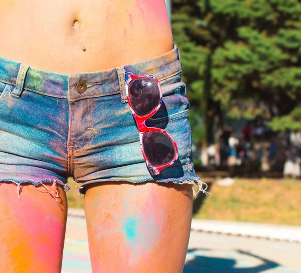 Girl in denim shorts at the festival of color Holi.