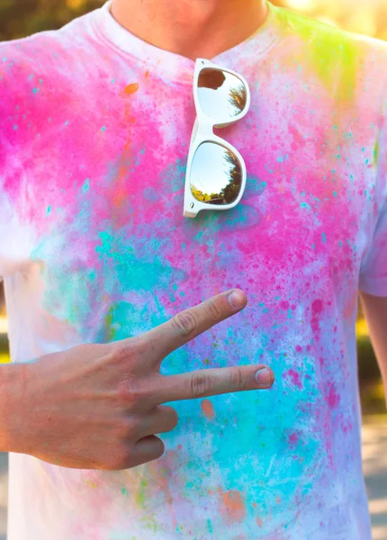 A young man shows the symbol of peace and friendship . Holi fest