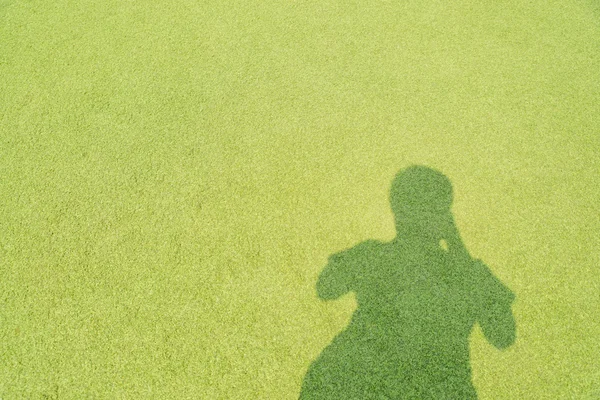 Stress, headache, health care and people concept: man\'s shadow projected on green grass with hand to his head