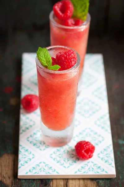 Homemade summer cold raspberry cocktail with crushed iced and alcohol in glasses on a vintage background