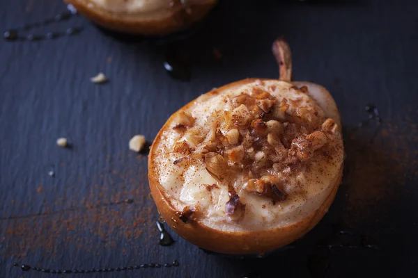 Baked pears with cottage cheese, honey and walnuts on dark background