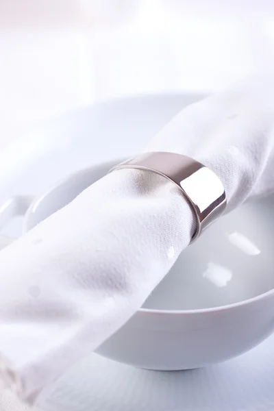 White textile napkin with ring on white ceramic bowl