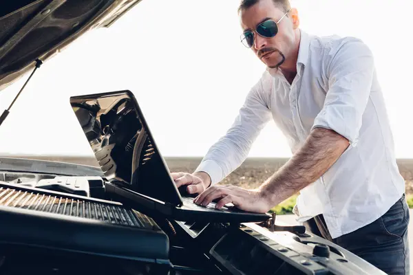 Man using a laptop repairing car