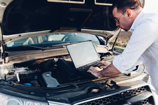 Man using a laptop repairing car