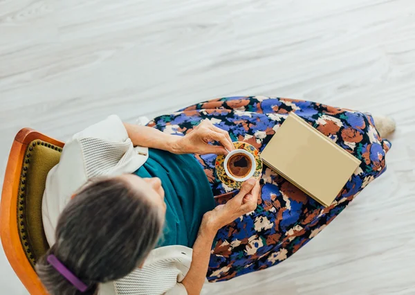 Top view of old woman with a cup of coffee and a book