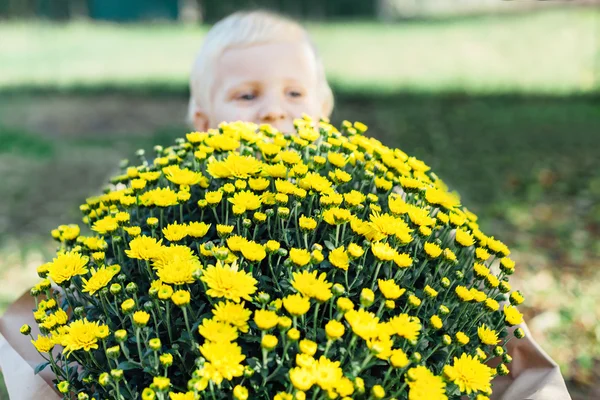 Happy boy holding a bouquet of yellow flowers