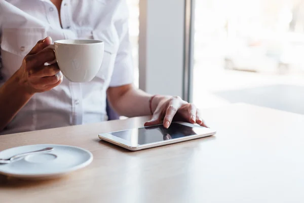 Woman drinking coffee and using tablet