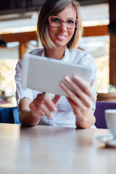 Happy woman using free internet on new tablet in a cafe