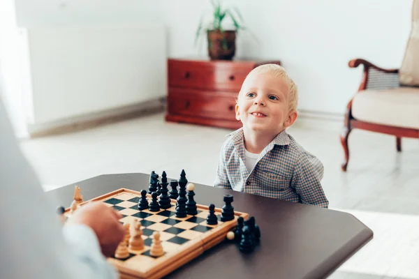 Boy learning to play chess at home