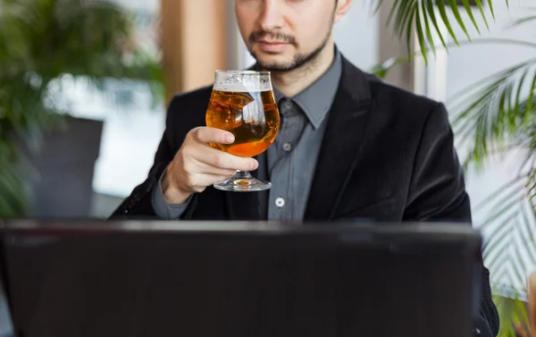 Man drinking beer and using laptop