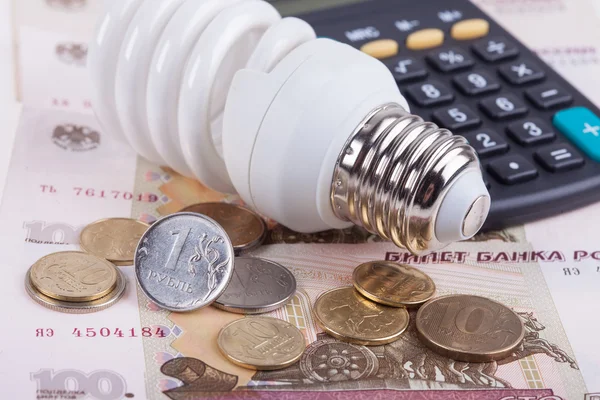 Energy saving concept. Electric light bulb, ruble money and calculator