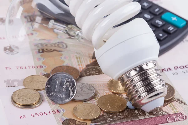 Energy saving concept. Electric light bulb, ruble money and calculator