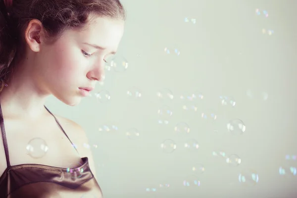 Beautiful girl in a gold dress with soap bubbles