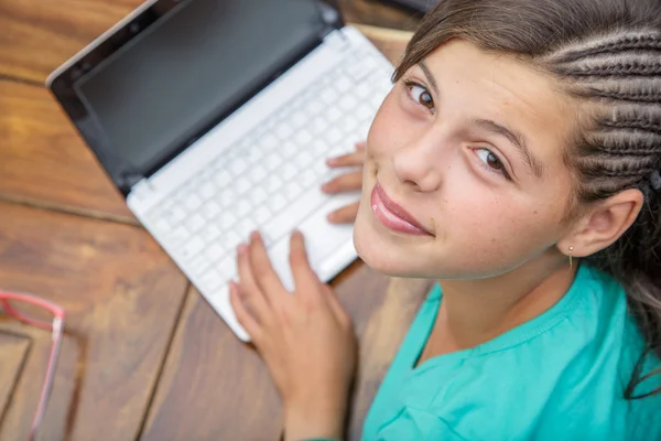 Closeup of pretty young girl smiling who types on a computer keyboard seen from above