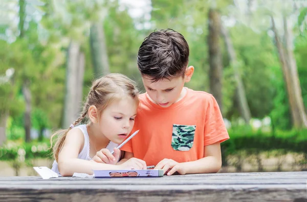 Hapy kids  learn in a park. Brother and sister together do the j