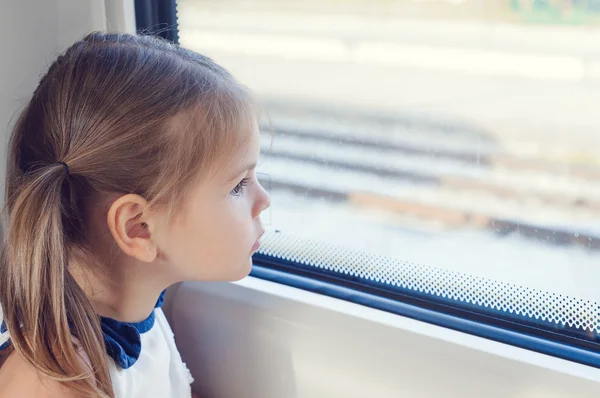 Little girl looking out the window of the train. She  looking through window, She travels on a train.