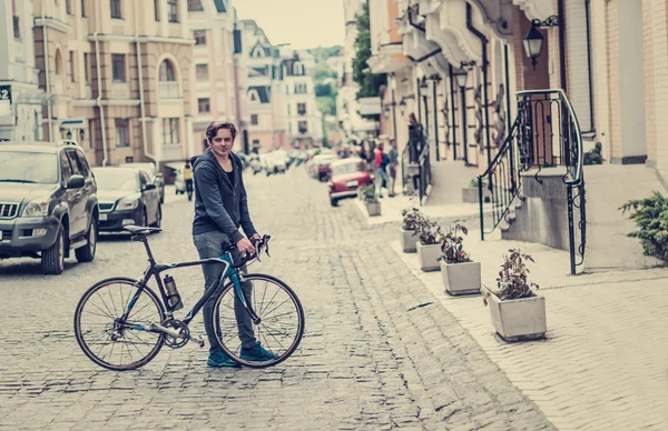 Young man with a bicycle on a city street