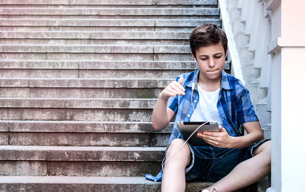 Teenager with tablet sitting on the stairs