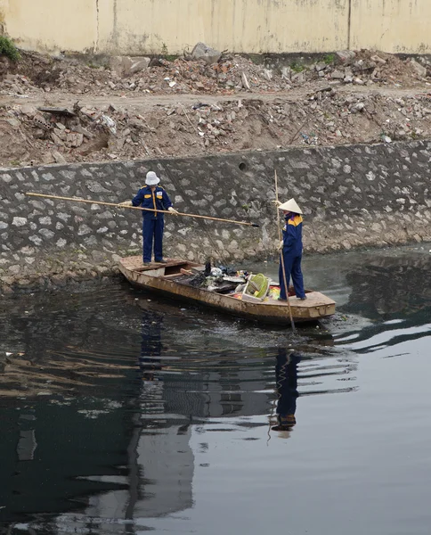 Vietnamese cleaner cleaning a polluted canal