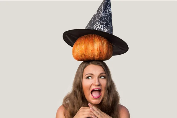 Scared young woman with halloween pumkin and witch hat on her he