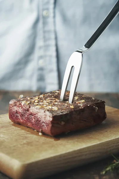 Grilled meat with steel fork inside isolated on board