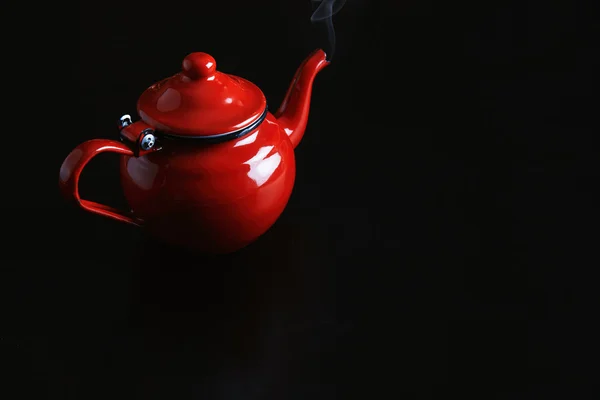 Top view, red enamel coated vintage teapot with hot beverage